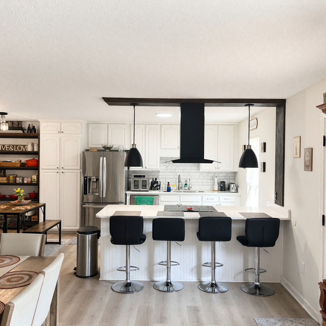 Remodeled open kitchen with island seating, black range hood, and white cabinets