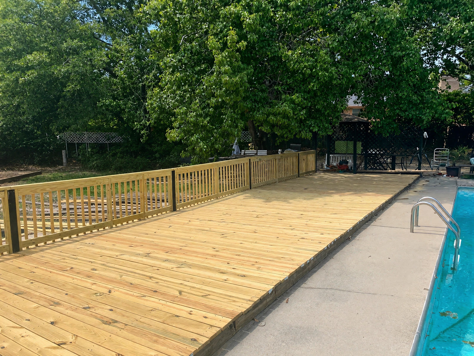 New pressure-treated wood deck built alongside a backyard pool