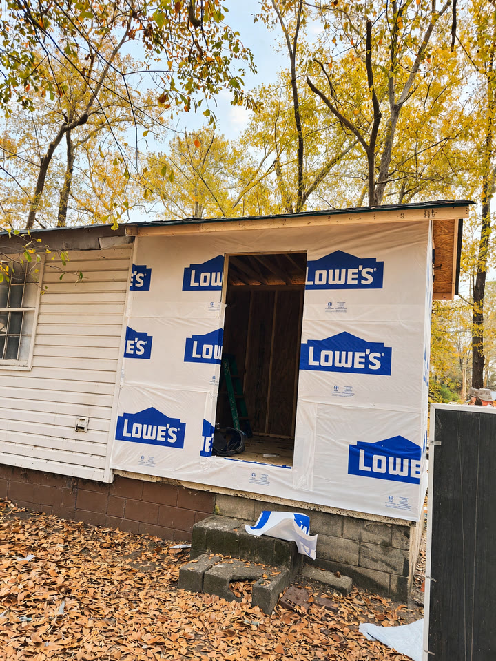 Addition framed and wrapped in Lowe's housewrap, door opening cut, leaves down in the yard