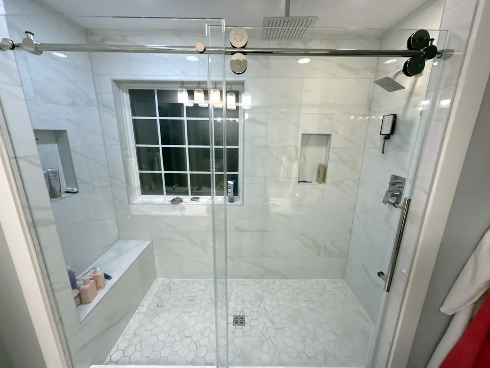 Marble walk-in shower with a glass slider and bench